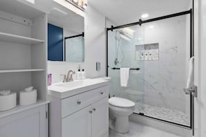 A modern bathroom with a glass shower enclosure, a white sink, and a toilet.