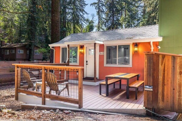 A small cabin with a deck, a wooden fence, and a bench.