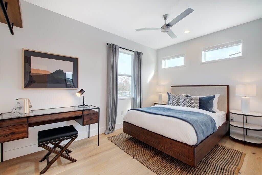 A bedroom with a bed, desk, chair, and a ceiling fan.