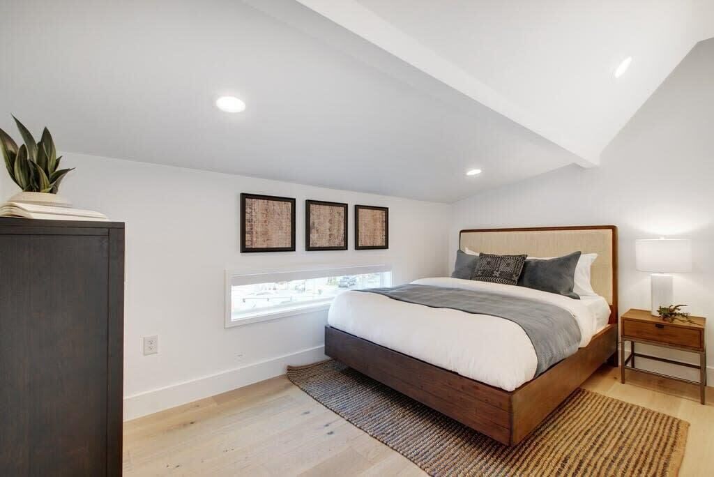 A bedroom with a large bed, a window, and a ceiling with exposed beams.