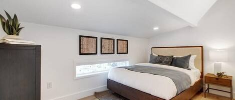 A bedroom with a large bed, a window, and a ceiling with exposed beams.