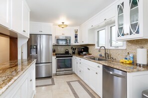 Enjoy cooking in this well-equipped kitchen with a refrigerator, microwave, oven, sink, and coffee maker.
