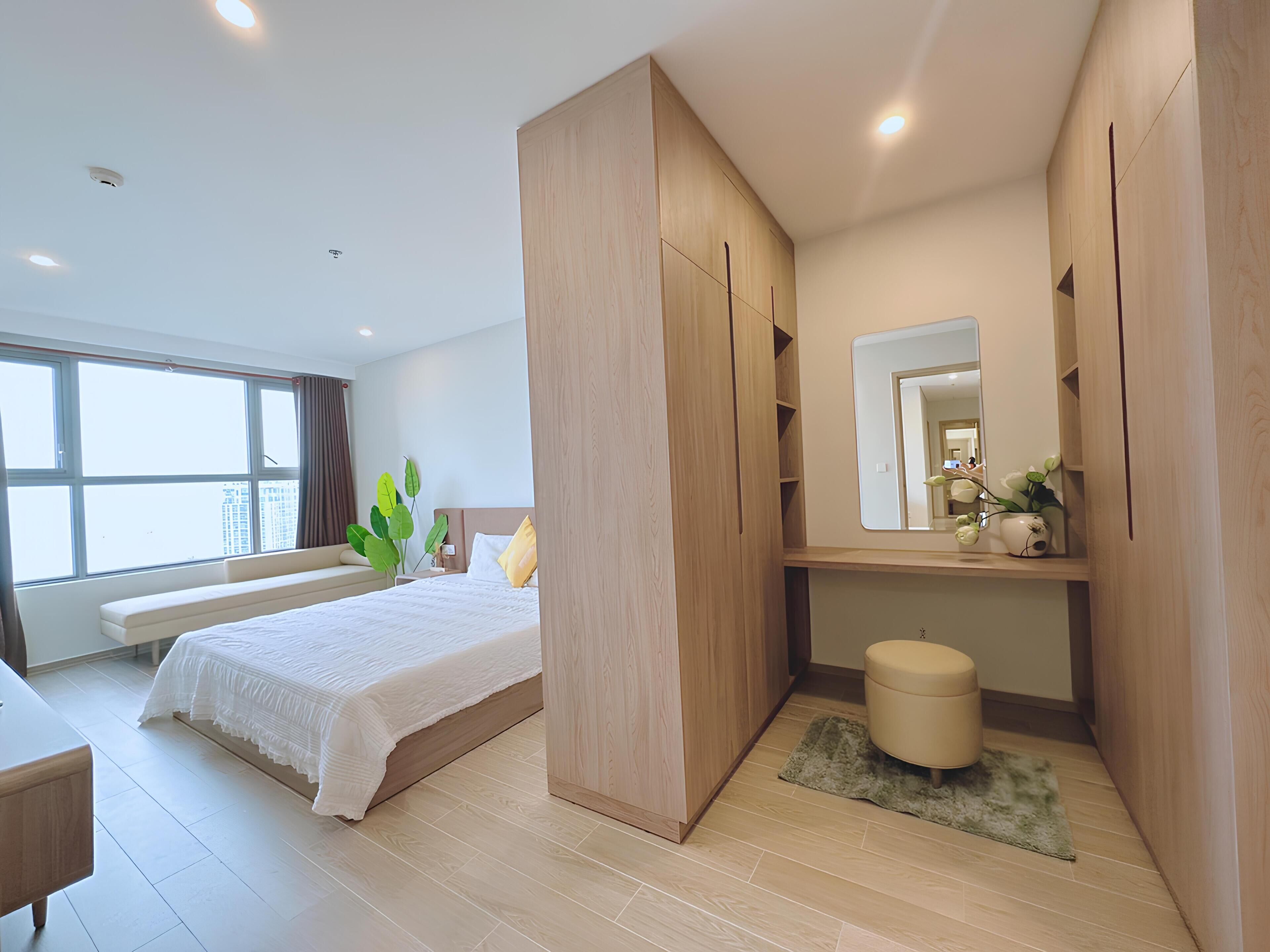 Un dormitorio moderno con una cama grande, armario empotrado, mesita de noche y un espejo.