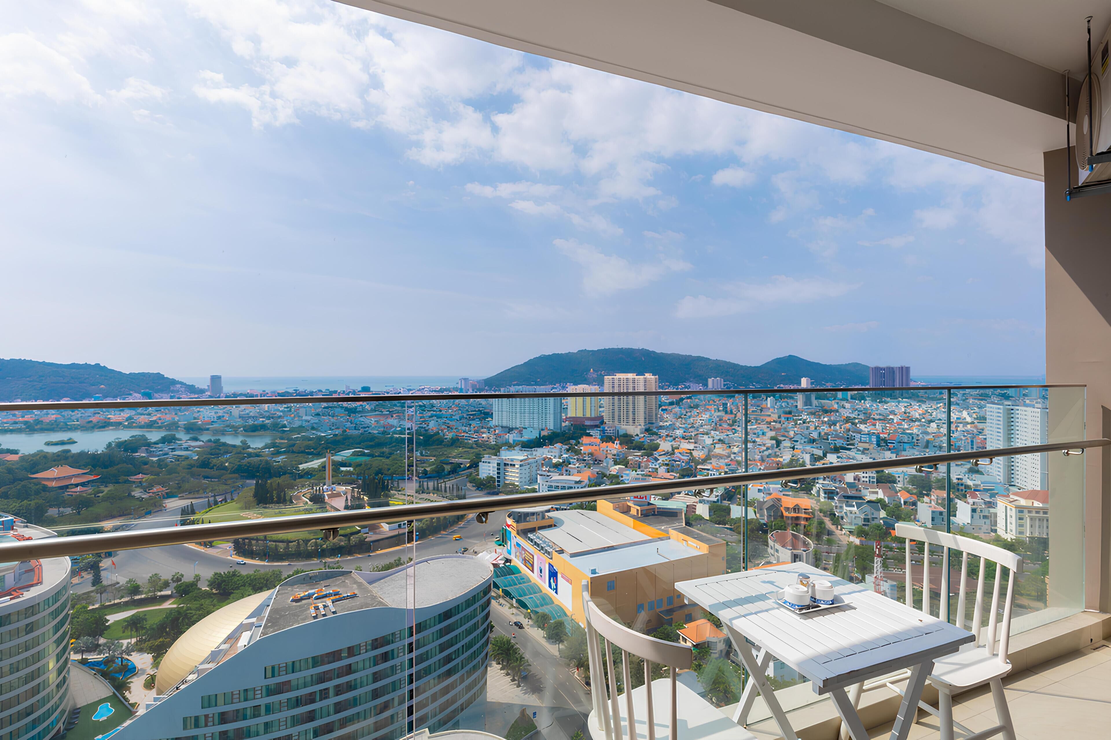 A balcony with a city view, including buildings and a mountain in the distance.