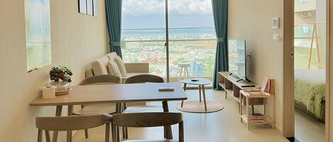 Una sala de estar moderna con comedor, ventanas amplias y vista a la ciudad.