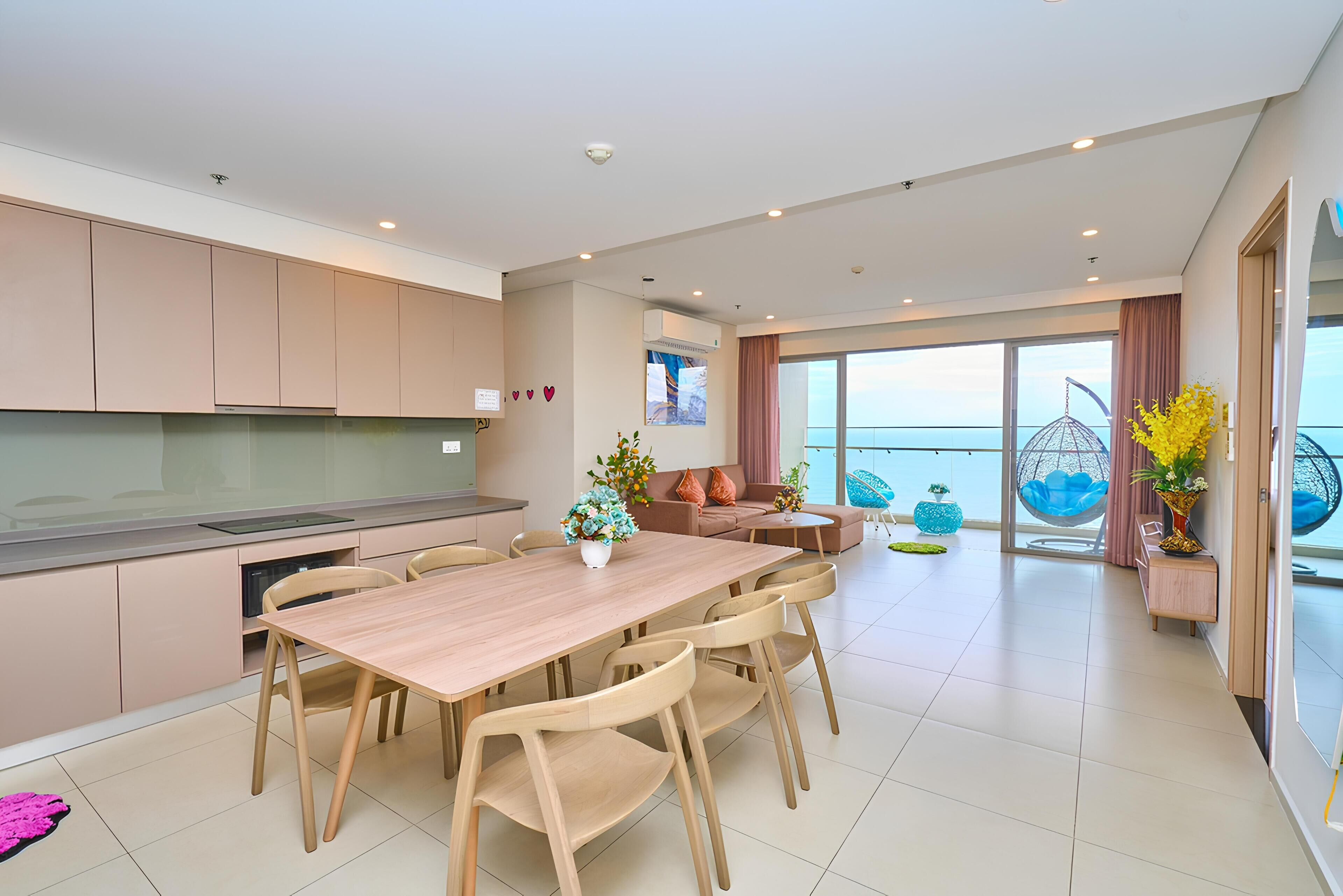 A modern living room with a dining area, large windows, and a view of the sea.