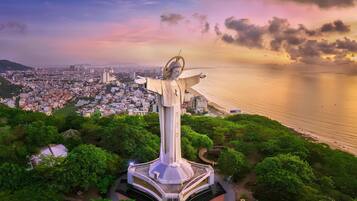 Una gran estatua de brazos extendidos dominando un paisaje urbano costero.