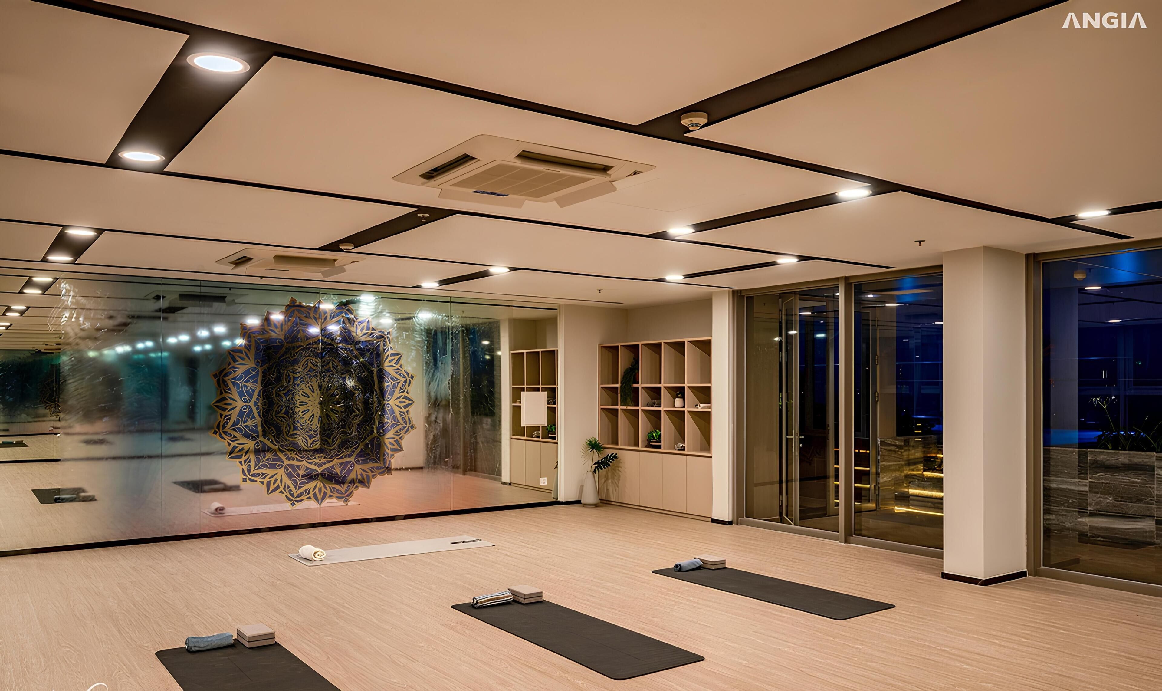 Un gimnasio moderno con suelos de madera, colchonetas de ejercicio y un espejo grande.