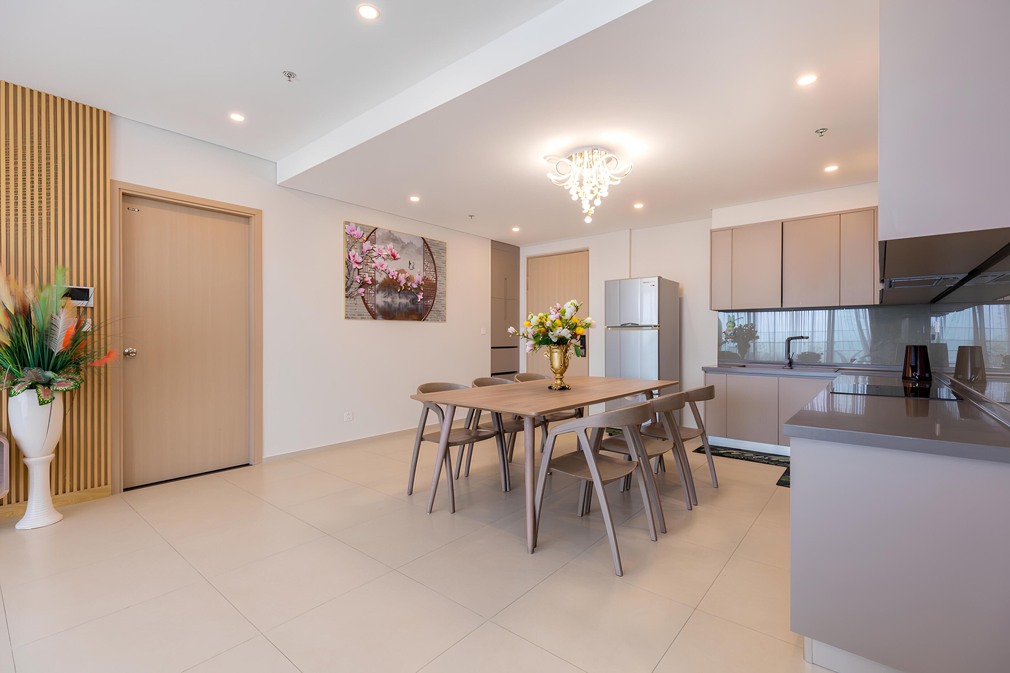 A modern kitchen with a built-in oven, a refrigerator, and a dining area with a wooden table and chairs.
