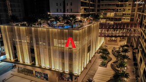 Un hotel moderno con una fachada vertical perforada distintiva y un llamativo logotipo rojo en forma de 'A'.