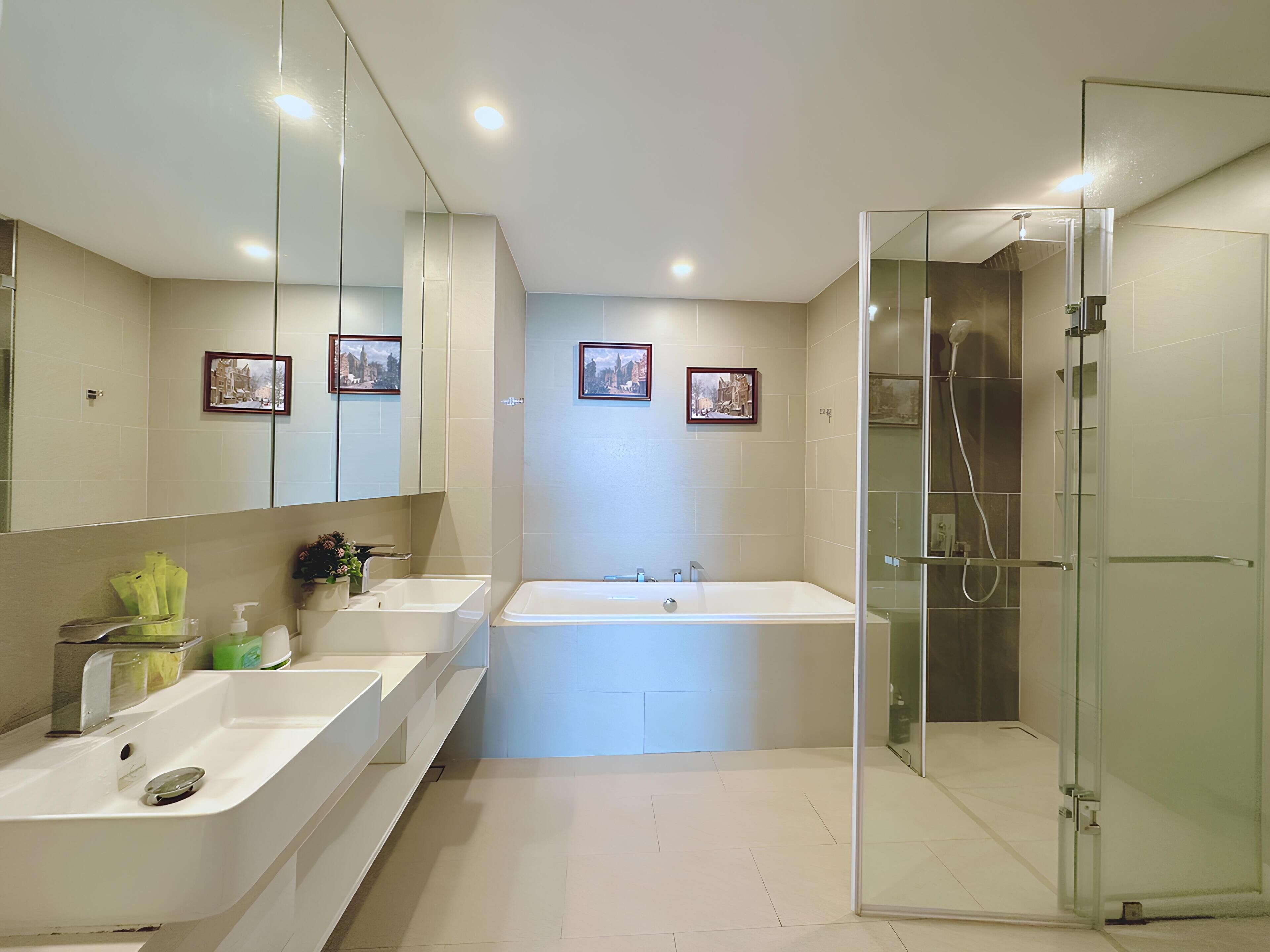 A modern bathroom with two sinks, a large bathtub, and a glass-enclosed shower area.