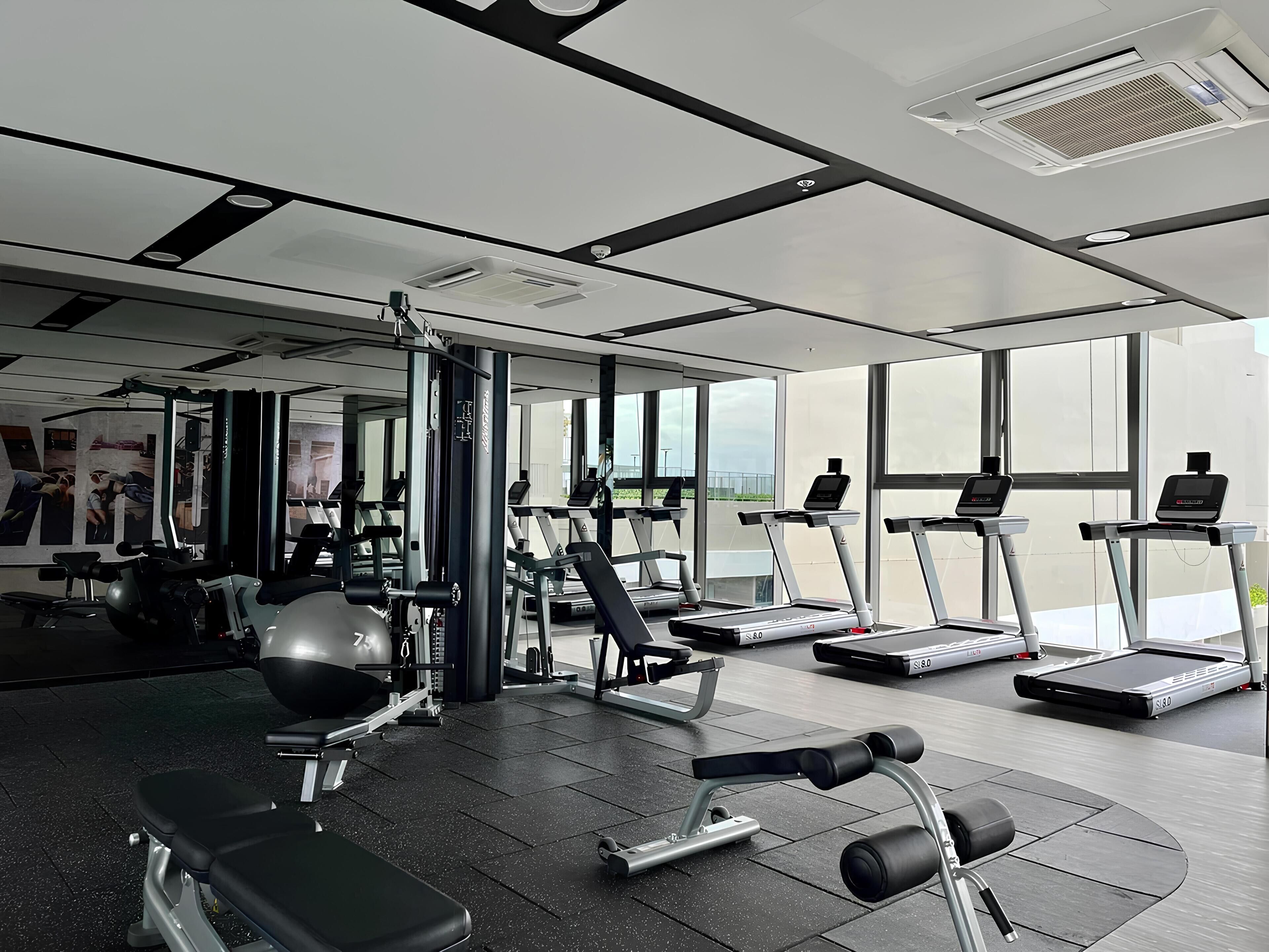 A modern gym with treadmills, weight machines, and a bench.