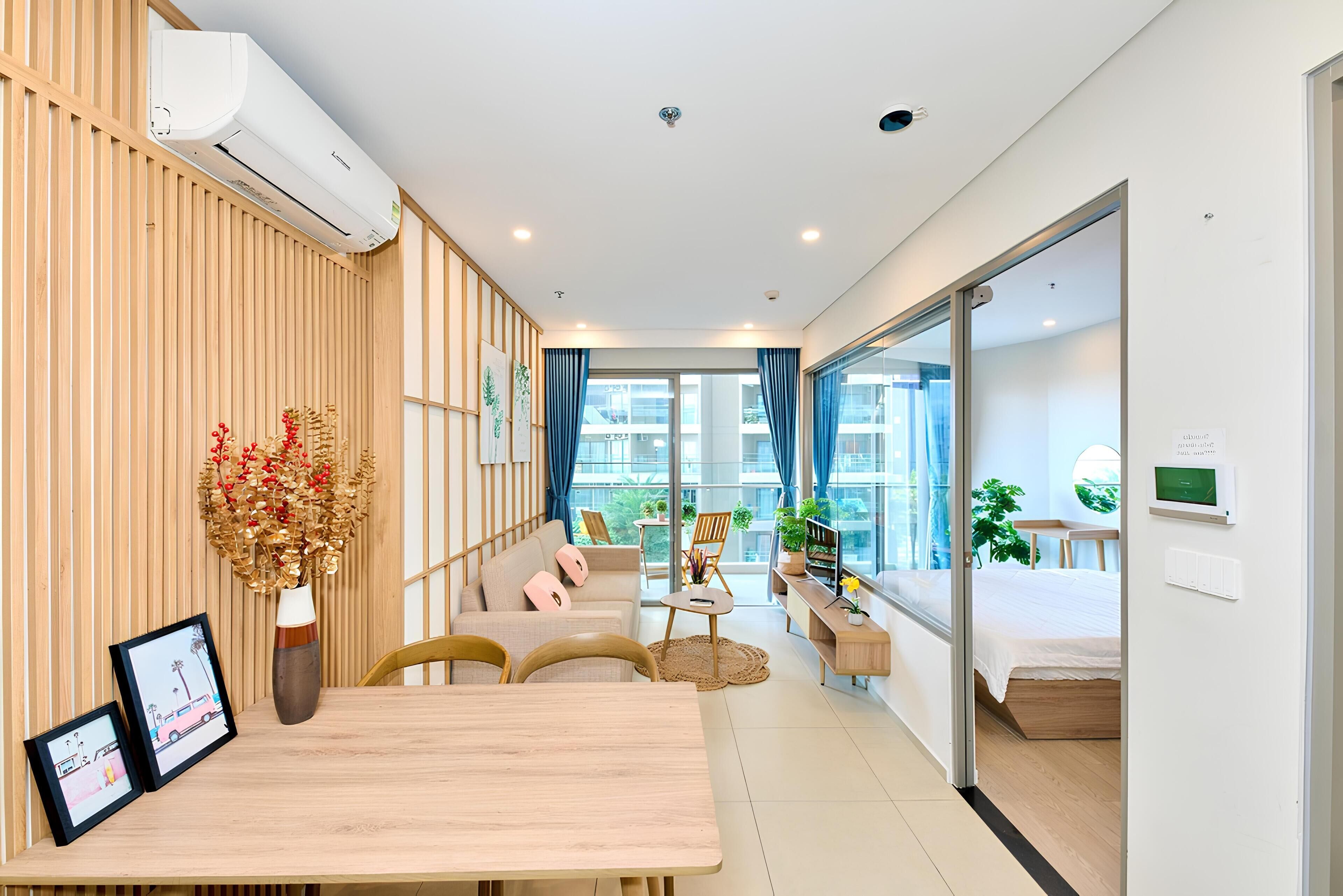 A modern hotel room with a wooden wall, a sofa, a dining table, and a bed.