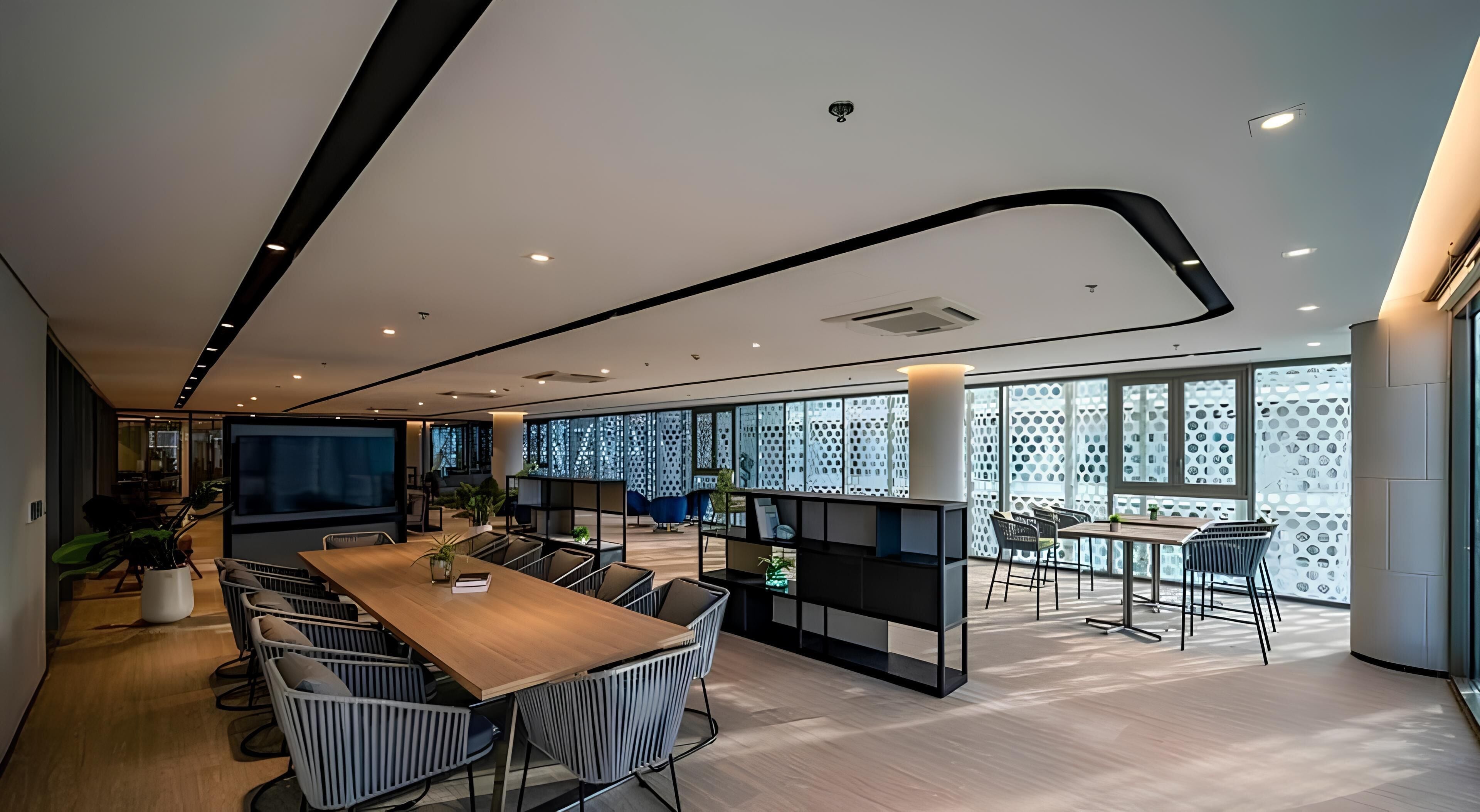 A modern conference room with a long table, chairs, and a projector screen.
