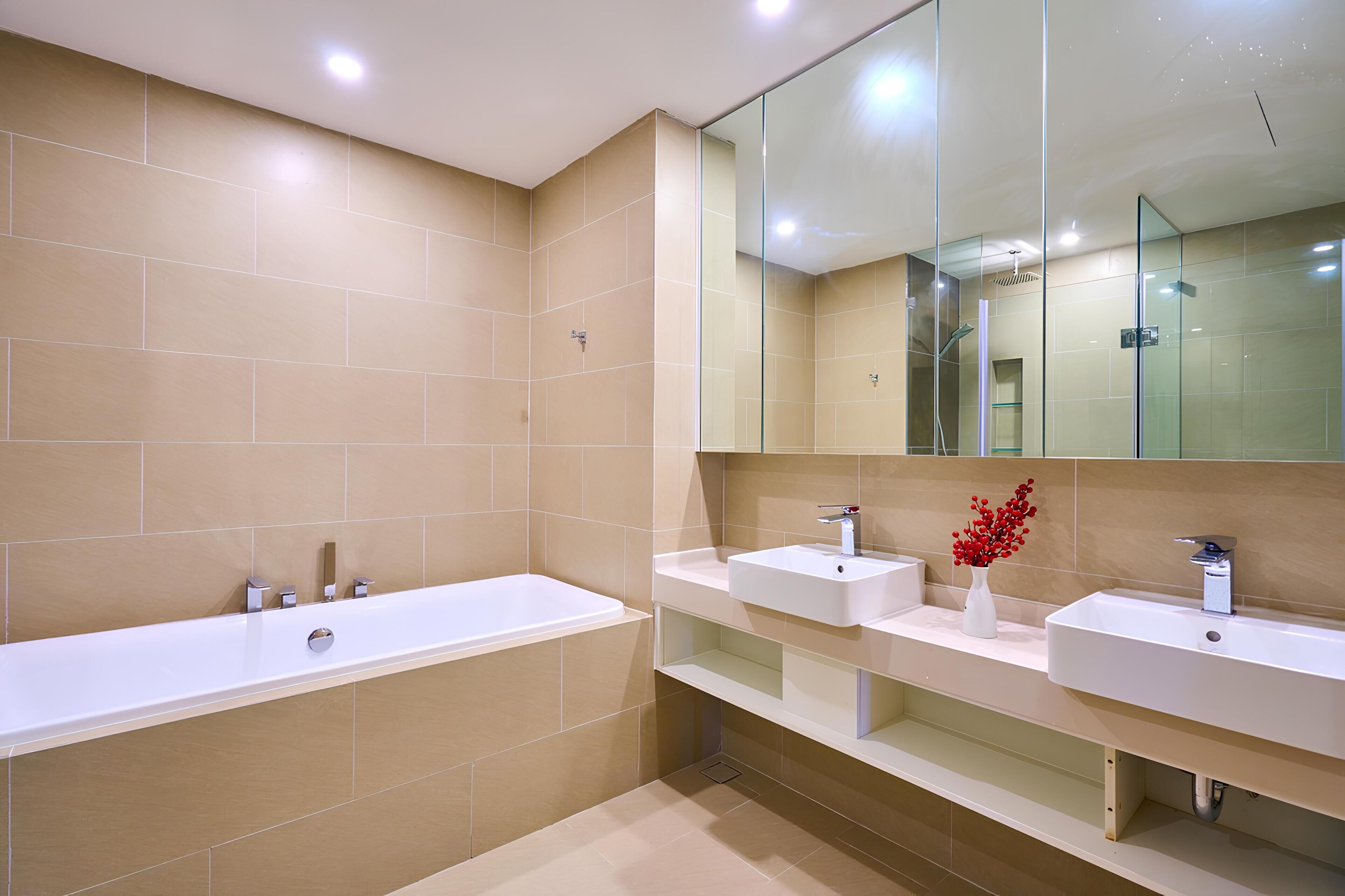 A modern bathroom with a large bathtub, two sinks, and a mirror.