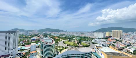 A cityscape with modern buildings, a roundabout, and a view of distant hills.