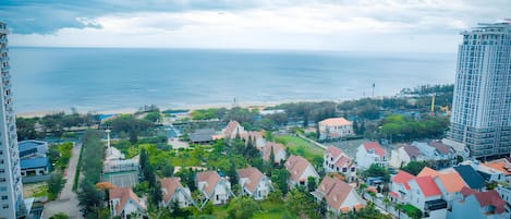 Zona residencial costera con casas, una playa y un edificio alto al fondo.