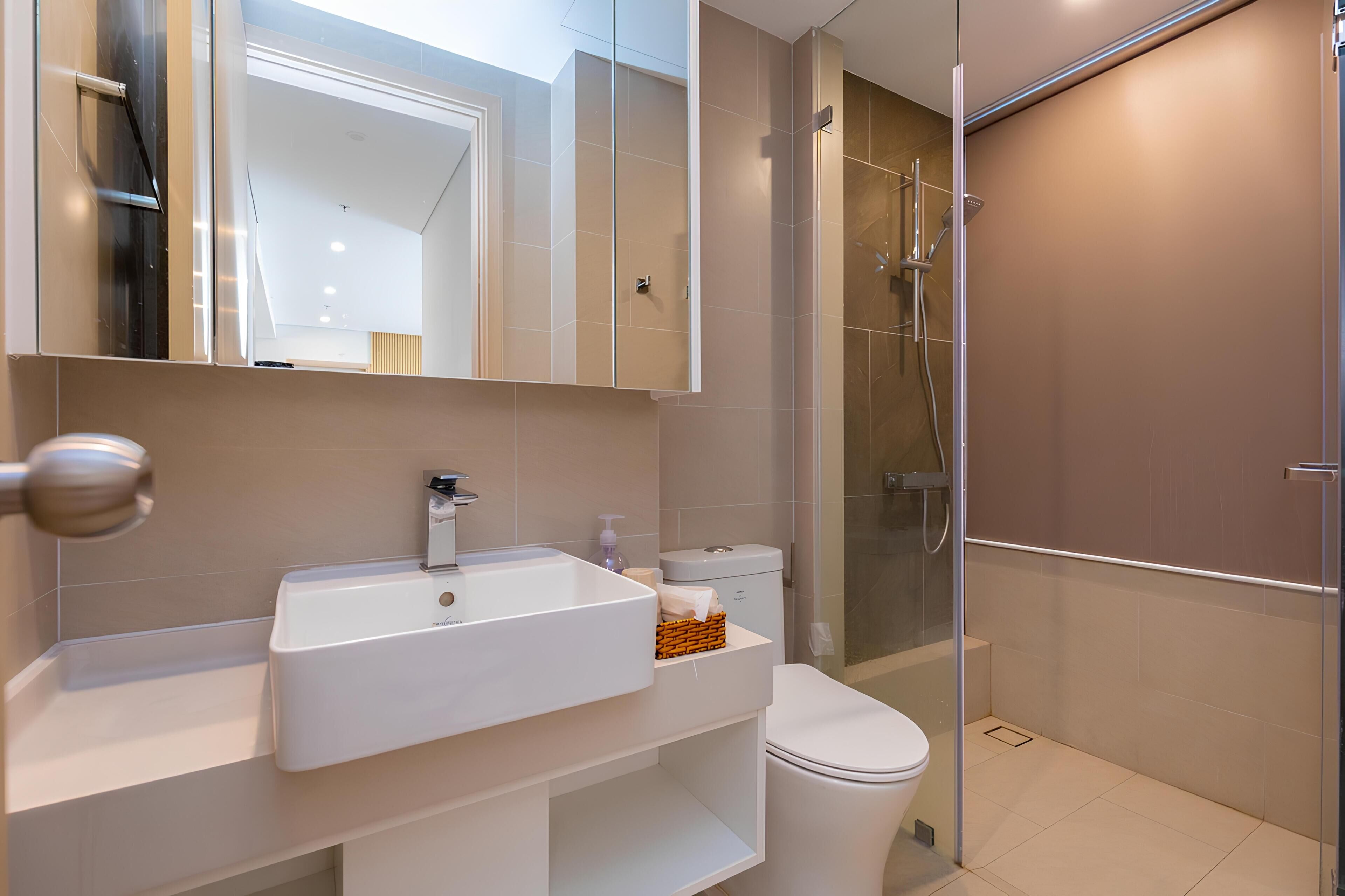 Un bagno moderno con lavandino bianco, water e cabina doccia in vetro.