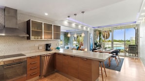 A modern kitchen with a large island, built-in appliances, and a dining area with a view of the outdoors. - Stunning 2BR/3Beds Lux Condo w/ Private Pool at Sunset 13 by Bocobay (Noord)