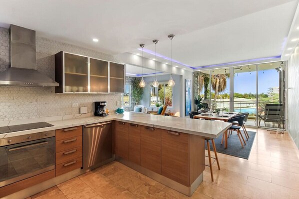 Una cocina moderna con una isla grande, electrodomésticos integrados y un comedor con vistas al exterior.