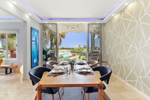 A dining area with a wooden table set for six, surrounded by black chairs.
