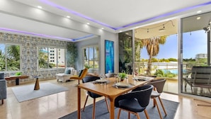 A modern dining area with a wooden table and black chairs, large windows, and a view of a pool and greenery. - Stunning 2BR/3Beds Lux Condo w/ Private Pool at Sunset 13 by Bocobay (Noord)