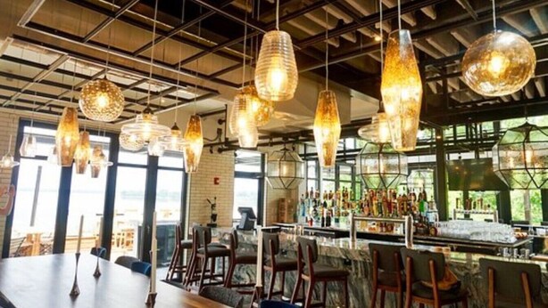 A restaurant with hanging pendant lights, a bar area with bottles, and a seating arrangement with tables and chairs. - Charming, Private Abode: Serenity in Hopewell, VA! (Hopewell)