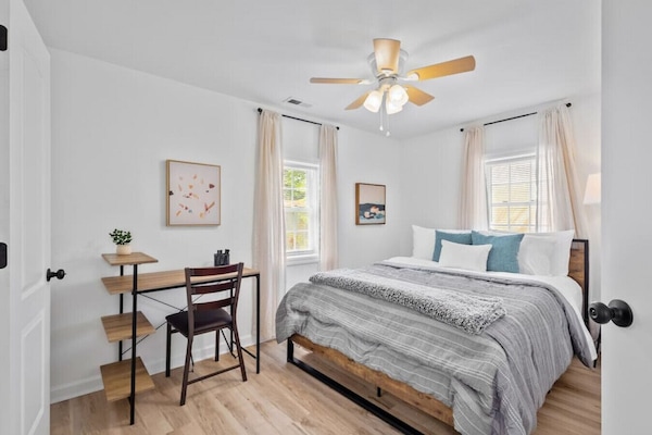 Peaceful master retreat with queen bed, ensuite bath & workspace. Unwind in this serene bedroom featuring soft linens, a ceiling fan, closet storage, and a dedicated desk for remote work or journaling.