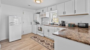A modern kitchen with white cabinets, a refrigerator, microwave, oven, and a toaster. - Charming, Private Abode: Serenity in Hopewell, VA! (Hopewell)