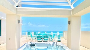 Een jacuzzi met uitzicht op de oceaan en ligstoelen.