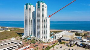 Een hoog hotel met uitzicht op de oceaan, met een parkeerplaats en een zwembad.