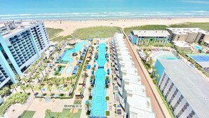 Een resort met meerdere zwembaden, een strand en hoge gebouwen.