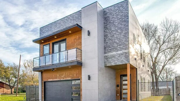 A modern two-story house with a garage, large windows, and a balcony.