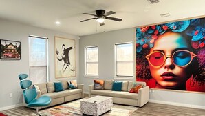 A modern living room with a sectional sofa, a unique blue chair, a coffee table, and a large abstract painting on the wall.