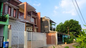 A residential building with a gated entrance, a balcony, and a small attached structure. - Alesya Homestay Syariah (Yogyakarta)
