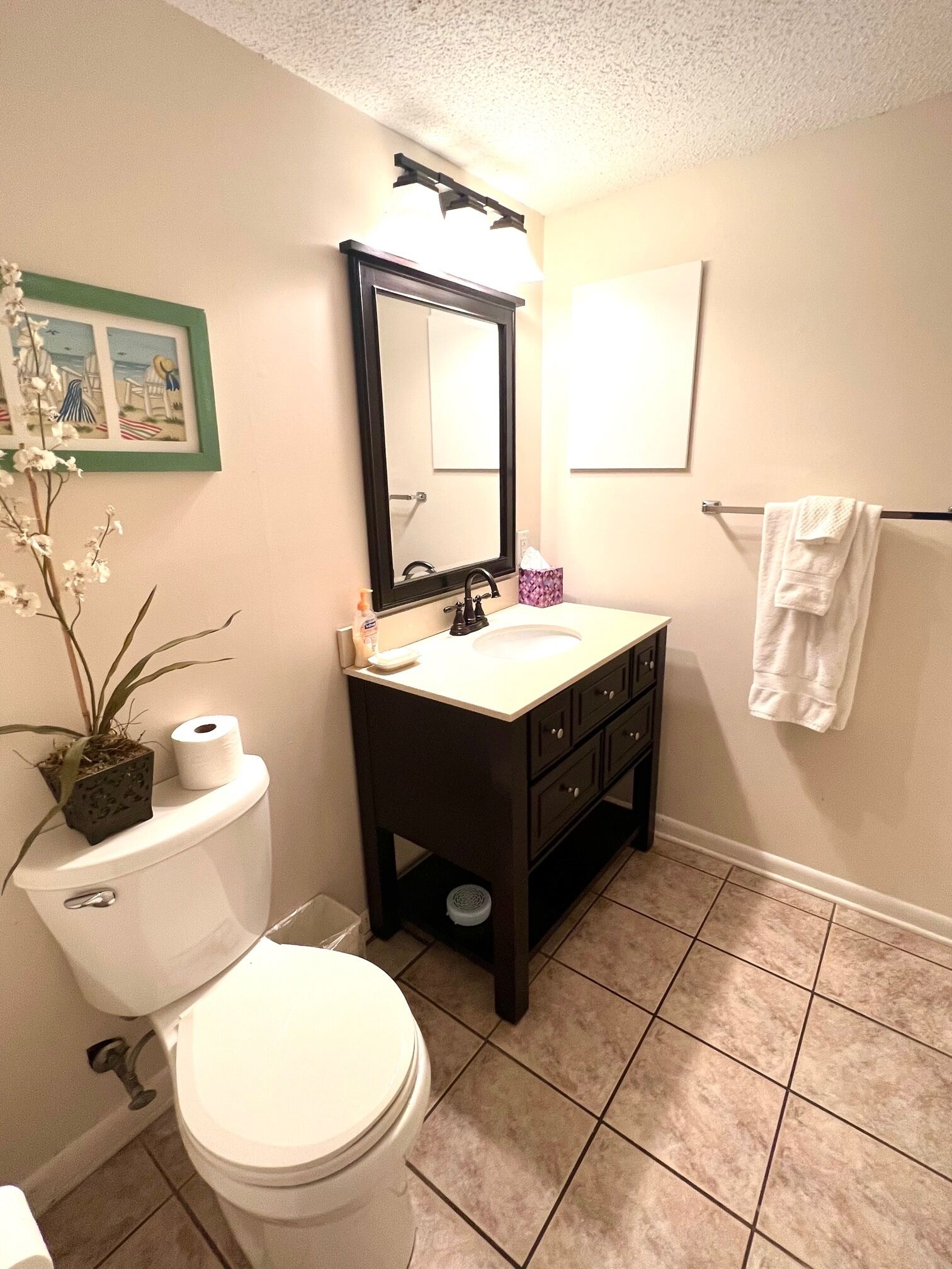 Un baño con inodoro, lavabo, espejo y toallero.
