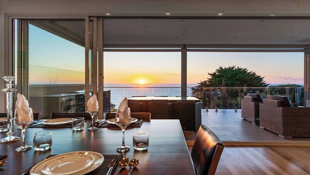 Uma área de refeições com mesa posta para dois, com vista para o pôr do sol.