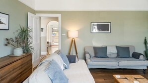 En stue med sofa, sofabord, lampe og en kaktus.