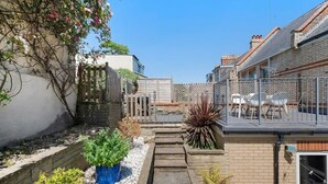 En boligejendom med lille have, en balkon med udendørs møbler og et murstenshus.