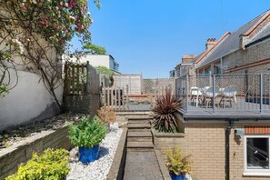 A residential property with a small garden, a balcony with outdoor furniture, and a brick house. - Spacious House & Garden in Ilfracombe (Ilfracombe)