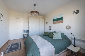 Une chambre à coucher avec un lit, une chaise, un bureau et un radiateur.