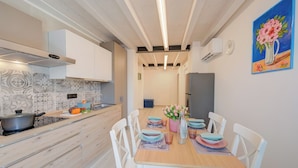 Una cocina moderna con armarios blancos, encimera de madera y un comedor con sillas blancas y mesa de madera.