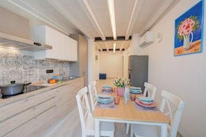 Une cuisine moderne avec des meubles blancs, un plan de travail en bois et un coin repas comprenant des chaises blanches et une table en bois.
