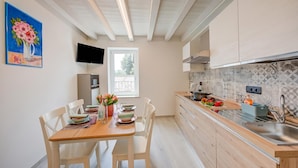 Una cocina moderna con armarios blancos, encimera de madera y pileta de acero inoxidable.