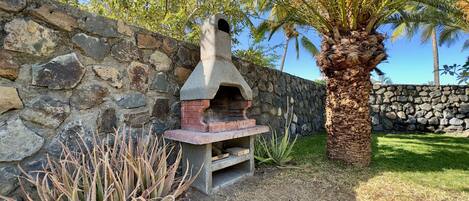 Un muro in pietra, un forno esterno in cemento e una palma.