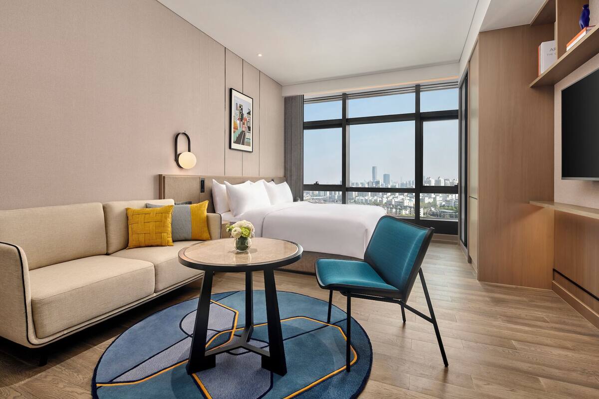 Een moderne hotelkamer met een groot bed, een sofa, een klein tafeltje en een stoel.
