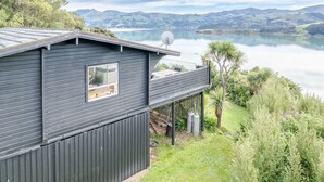 Ein dunkles Holzhaus mit Balkon mit Blick auf einen See und Berge.