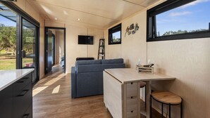 A modern kitchen with a wooden countertop, a grey sofa, and a dining area with a small table and stools. - Peace in Paradise - Tokerau Beach Holiday Home (Tokerau Beach)