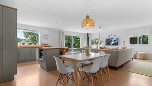 A modern kitchen with a dining area, grey cabinets, and a large window.