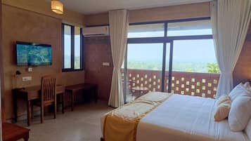 A hotel room with a bed, a desk, a chair, a television, and large windows with curtains.